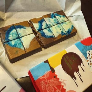Butter to Be Safe chocolate bar on a rustic wooden table with broken pieces revealing texture.